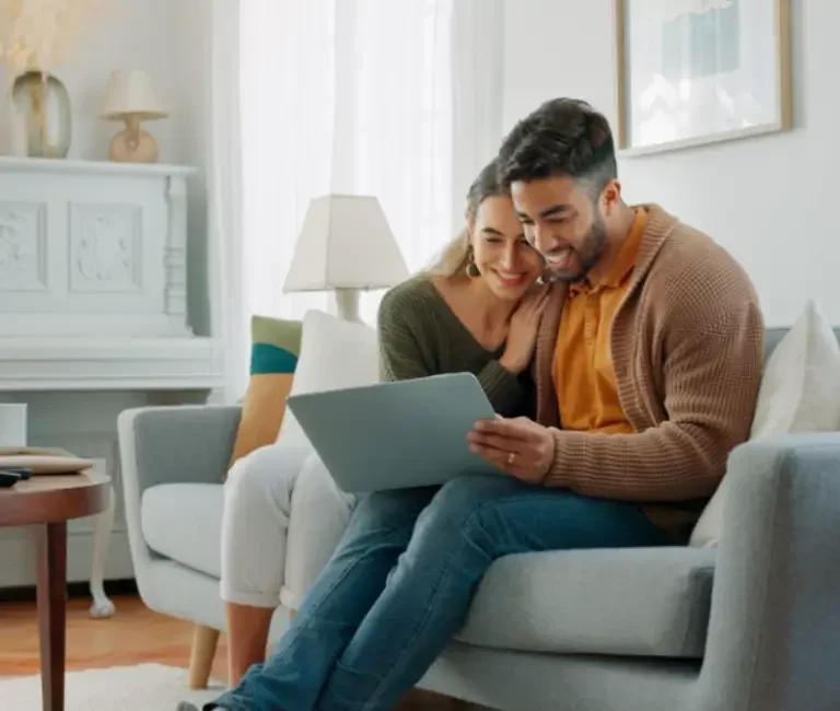 Ein Paar auf einer Couch, dass in Immobilienportalen nach einer passenden Immobilie sucht.